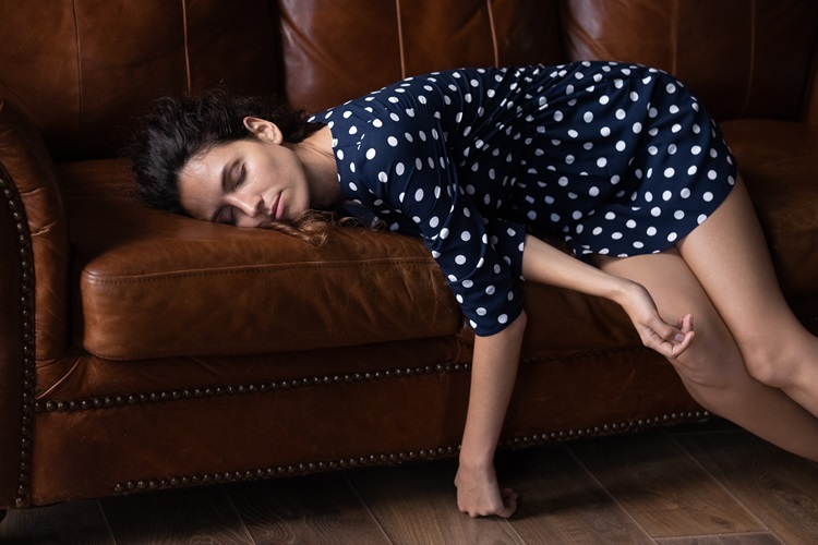 Slapende jonge vrouw op de bank met haar ogen dicht - dommelen, dagdromen, vermoeidheid en gebrek aan energie